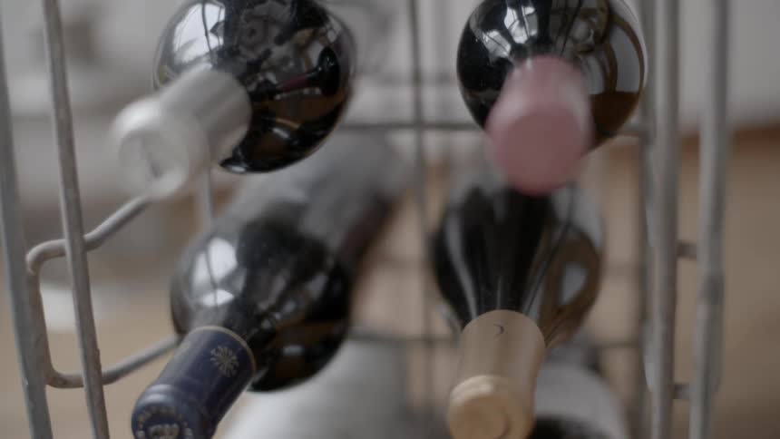 Bottles of red wine sit on a metal wire rack