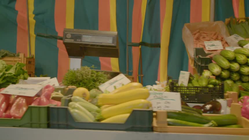 Shelves and bins at a vegetable market overflowing with various products