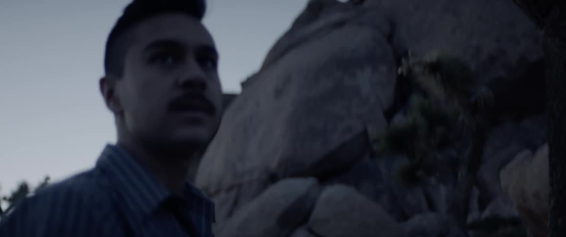 A man walks outside and gestures to someone