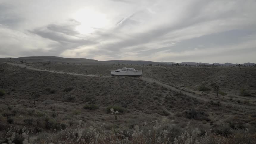 A boat sits in the middle of a dirt road in the desert