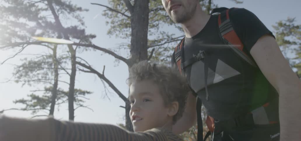 A little boy standing with his father points at something in the distance