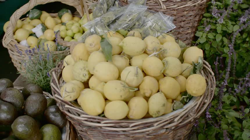 Baskets filled with fruit are stacked among a flower bed