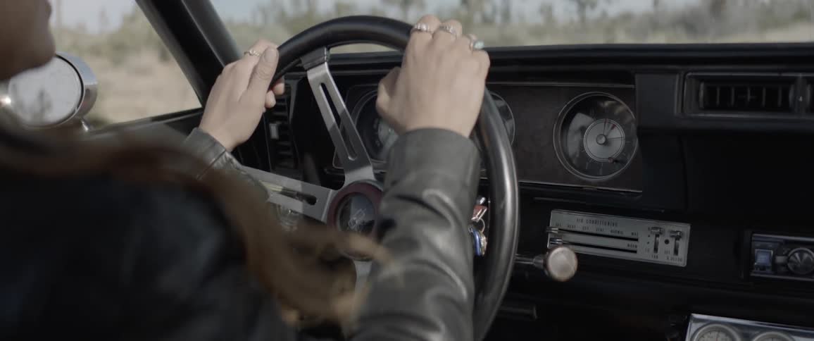 Female hands on a steering wheel in a vintage car