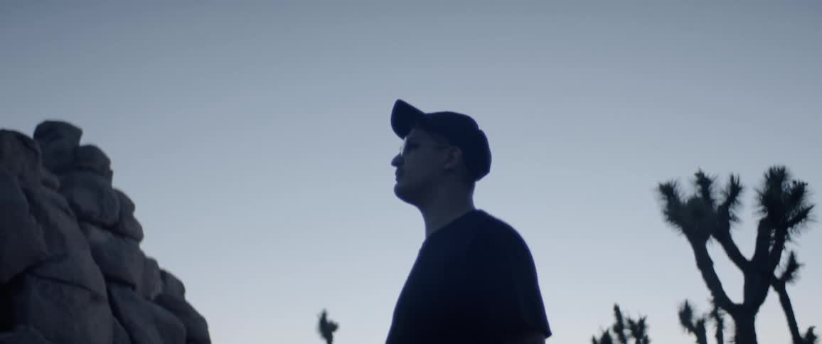 A man with cap standing near a pile of rock