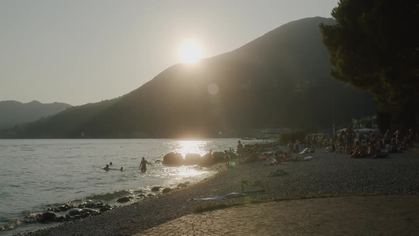 Lots of people sit on a beach watching while other people swim in the water