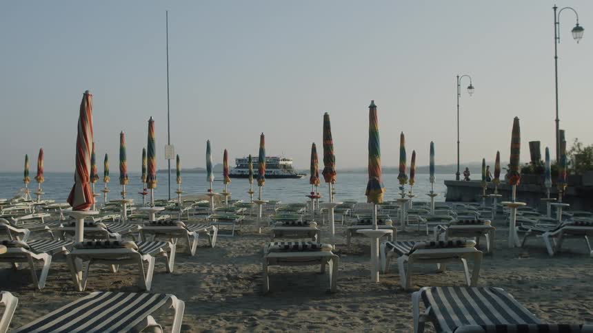 A cruise ship sails past a beach with chairs and umbrellas