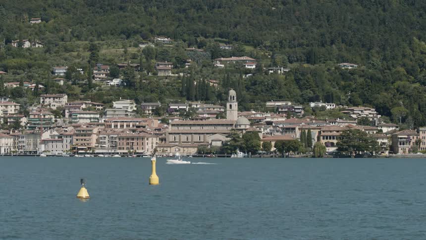 A speedboat travels through the water in front of a neighborhood