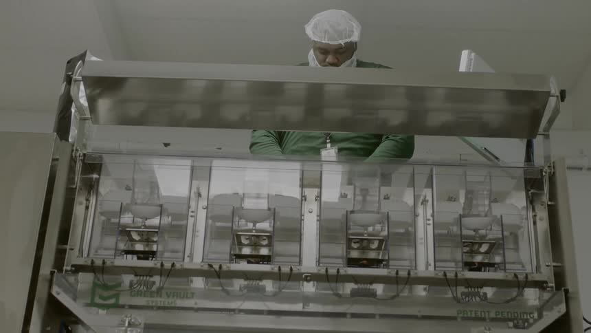 A man in scrubs uses a machine to dispense medicine