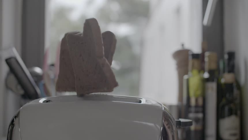 Toast is coming out of a toaster and falling