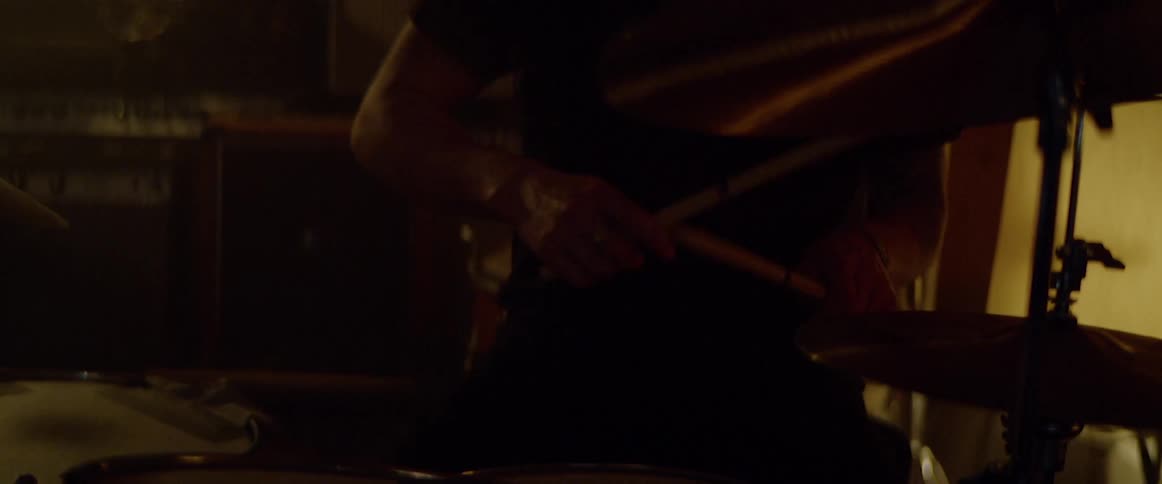 Drummer wearing a cap plays the drum in a dark room
