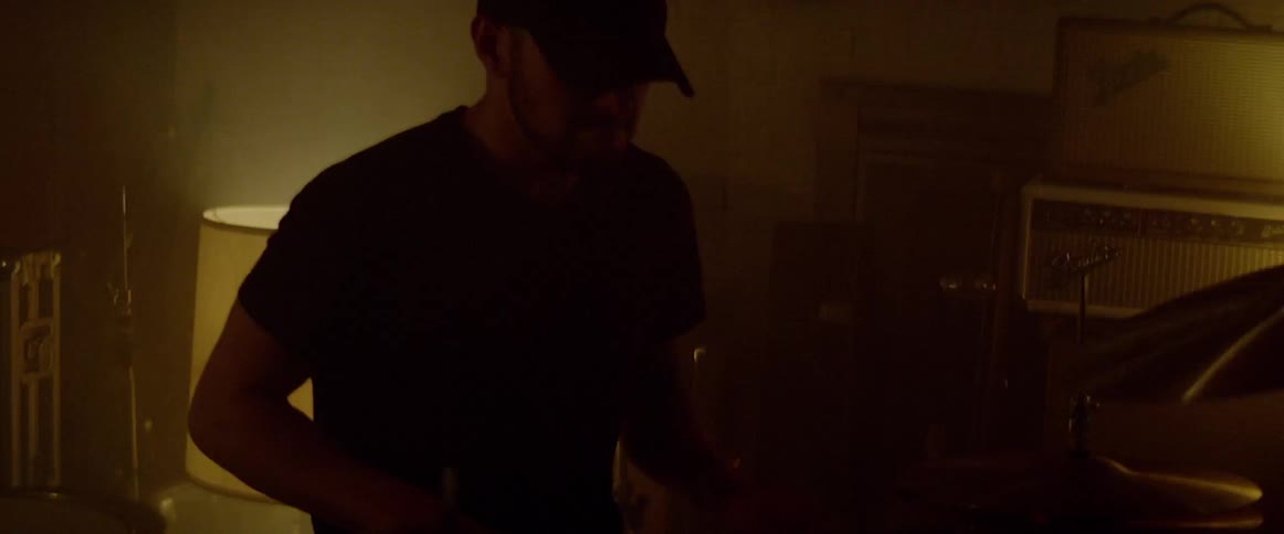 A drummer plays in a lowly lit studio