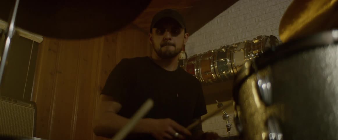 A man playing drums sitting in a room