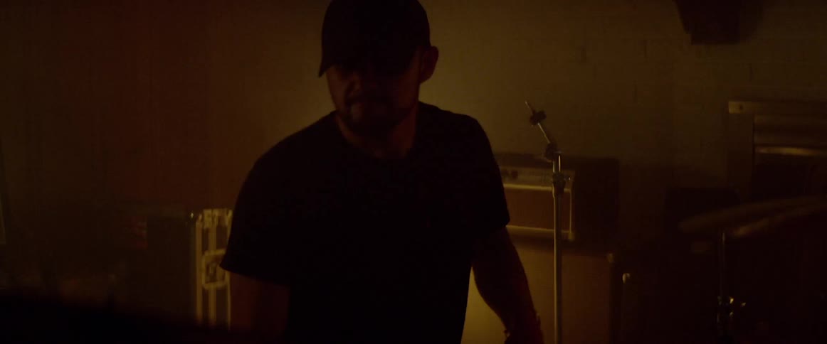 A man plays the drums in a dark room