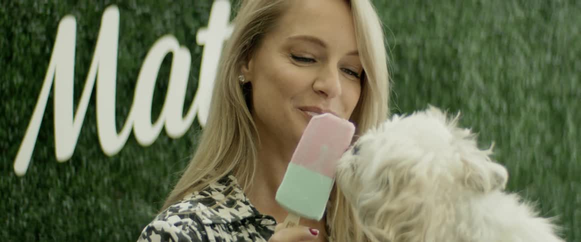 A woman letting a dog lick an ice cream treat