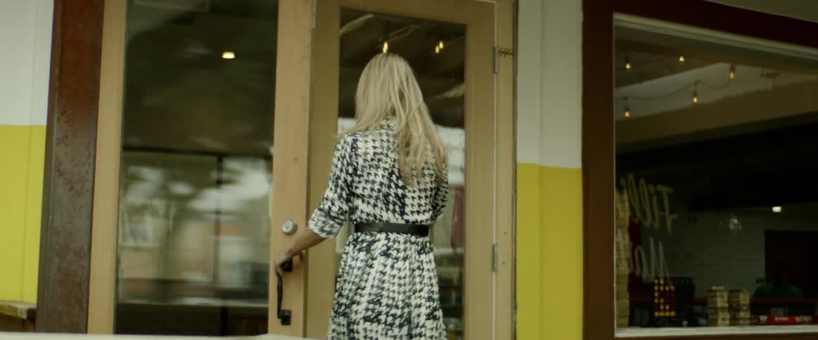 A woman walks past a billboard and enters a store