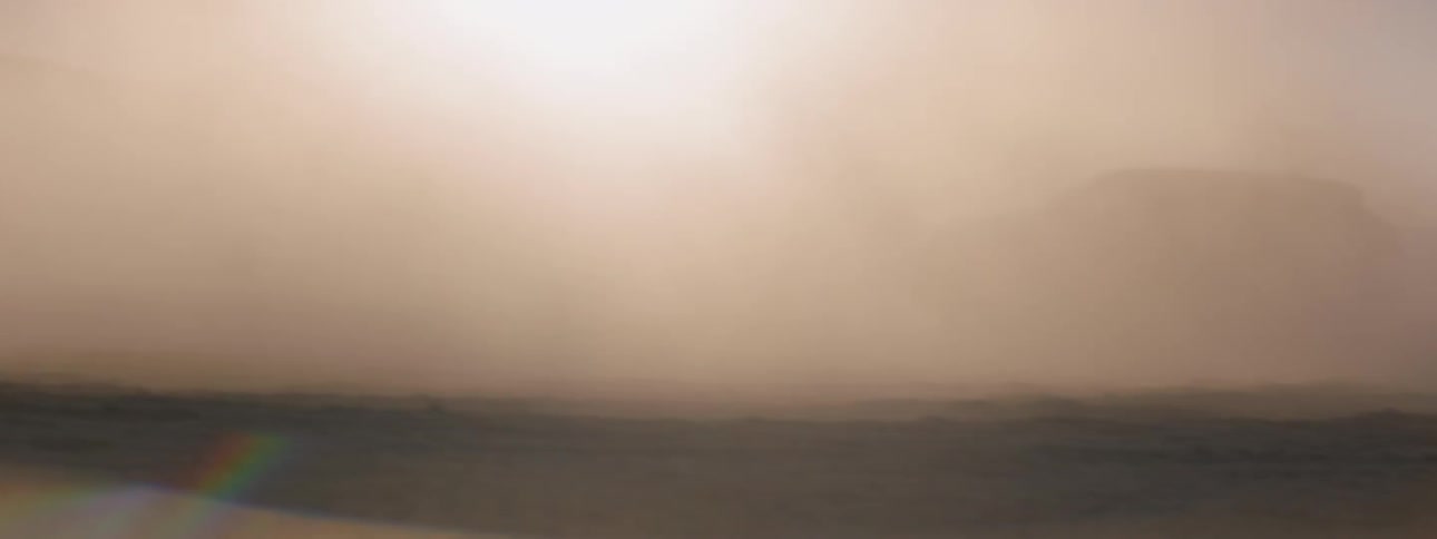 A black suv drives around a white suv and comes to a stop in a cloud of dust