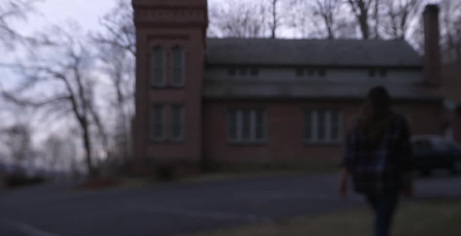 A woman walks towards a rural building