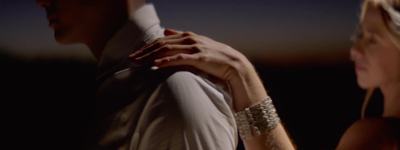 Blonde woman touches and turns around man in the spotlight outdoors