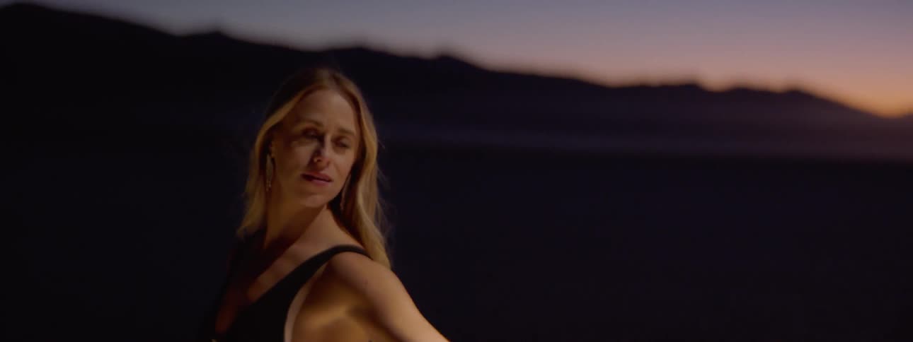 Blonde woman spins around man and dances in the spotlight outdoors