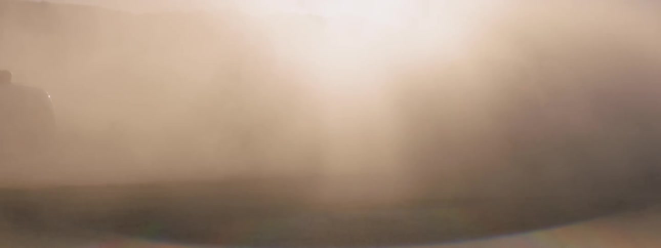 The sun shines through a cloud of dust created by suvs on the salt flats