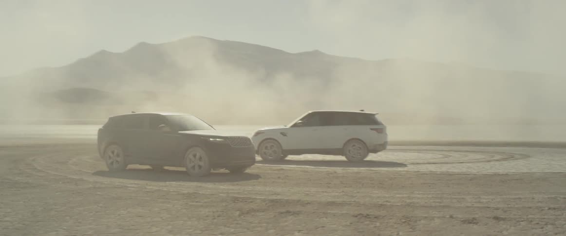 Two range rover sports on the salt flats are parked after creating a dust cloud