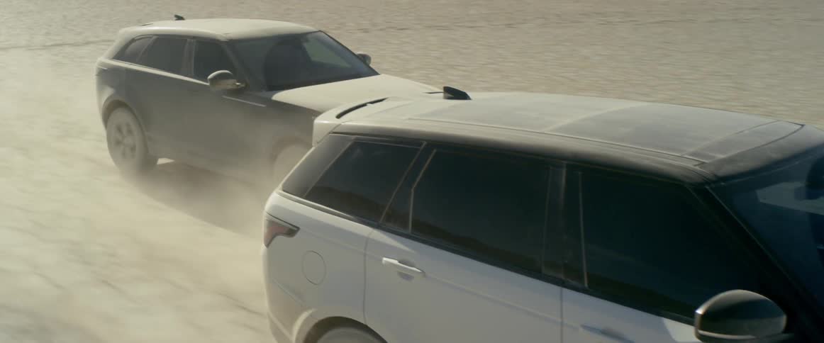 Two cars race through a flat desert