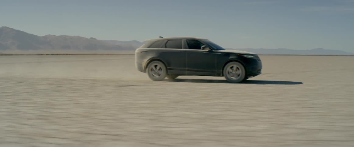 Black range rover sport drives through the desert covered in dirt