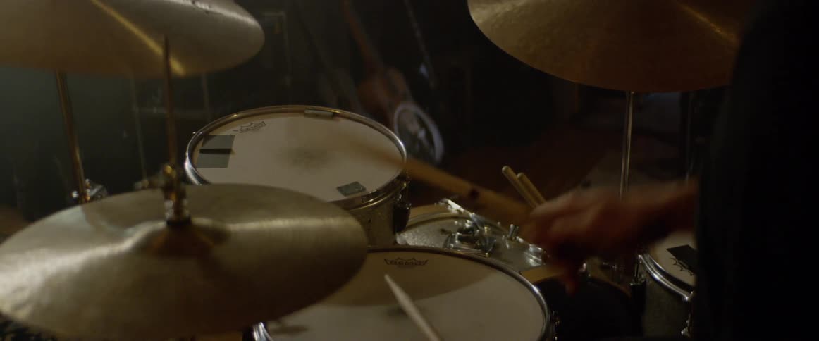 Man wearing a hat playing drums indoors