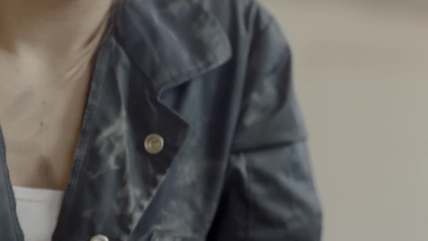 A young girl with dirt all over her face looks down at her hands clenched together