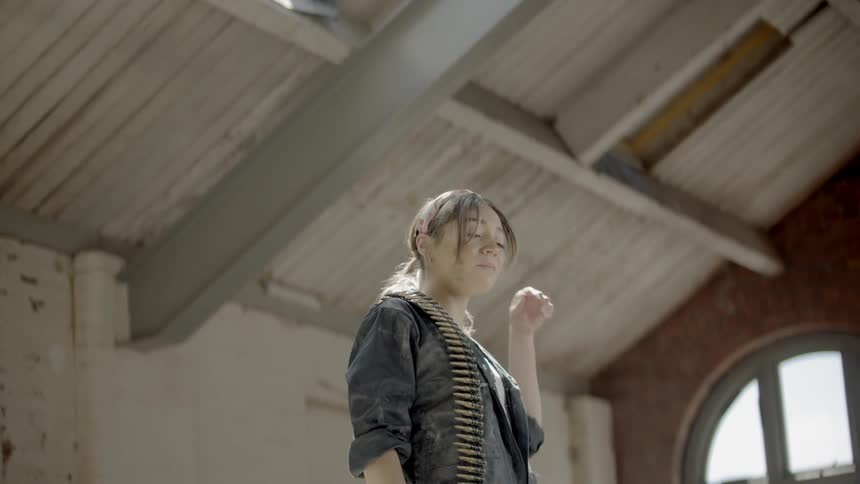 A woman is standing in a room with bullets across her shoulder