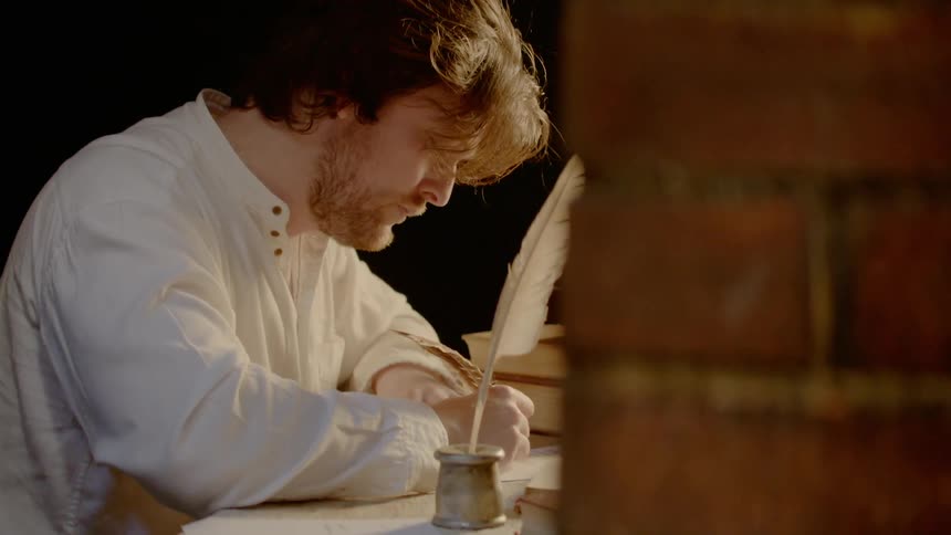 A man uses a feather and inkwell to write