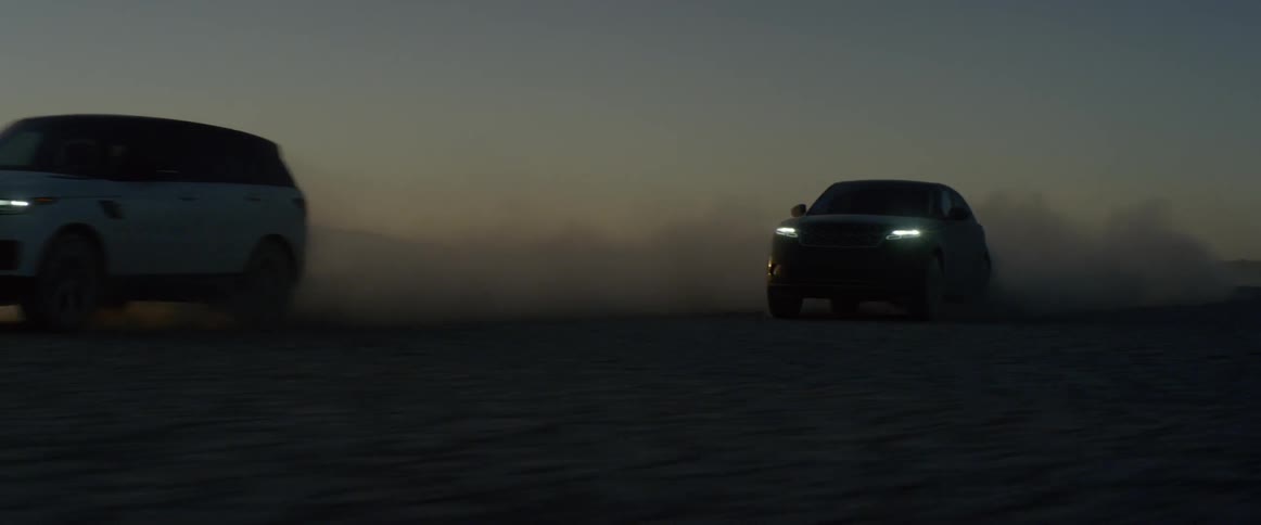 Two range rover sports on the salt flats kicking up dust at sunset