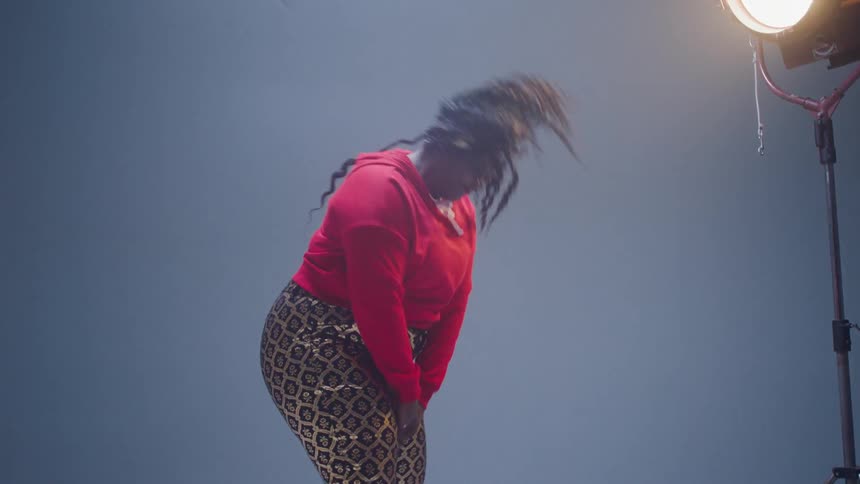 A woman swings her hair in a circle while standing in a studio