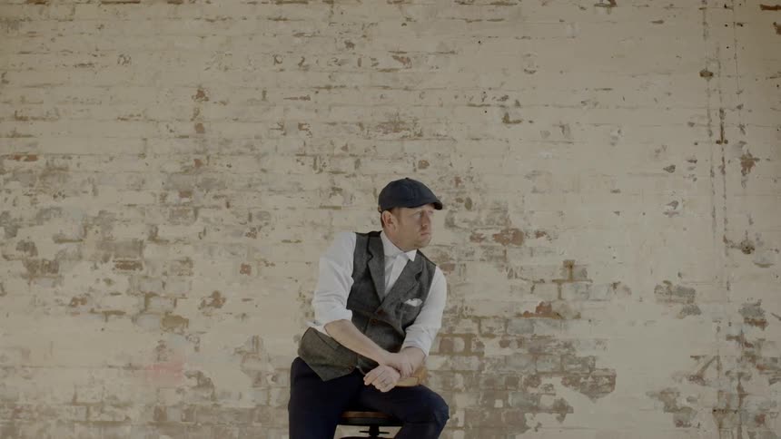 A man sitting on a stool next to a wall