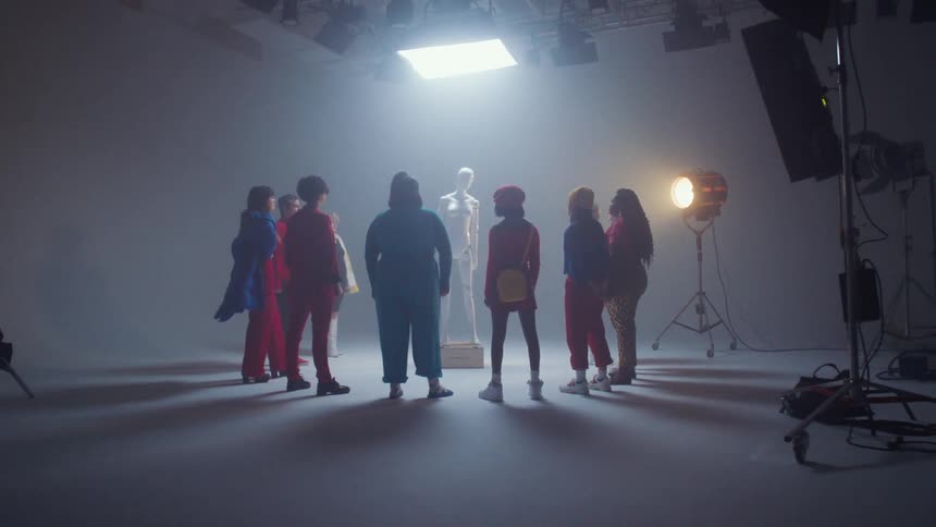 Group of people stand around a mannequin in a studio