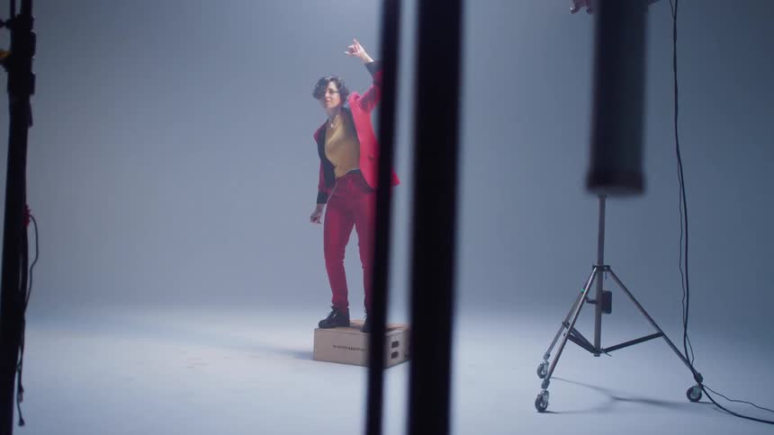A woman dances on a box in a studio under studio lighting