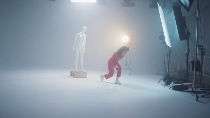 A person dancing in a studio next to a statue