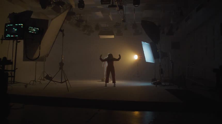 A woman poses and dances on stage while lights flash