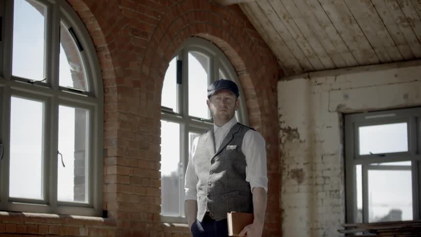 A man stands in an old building holding a book