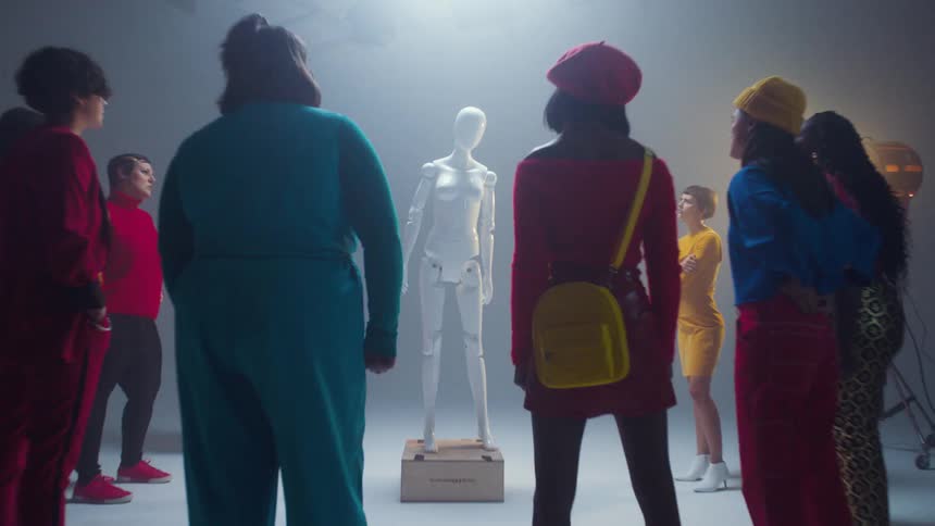 A group of people are standing in a circle with a robot