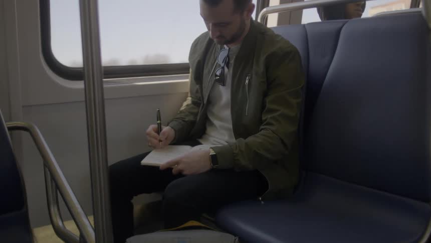 A man is writing in his notebook on the bus