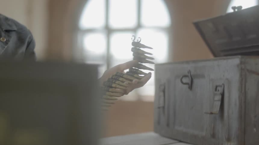 Man taking an ammunition belt from metal box and placing on table