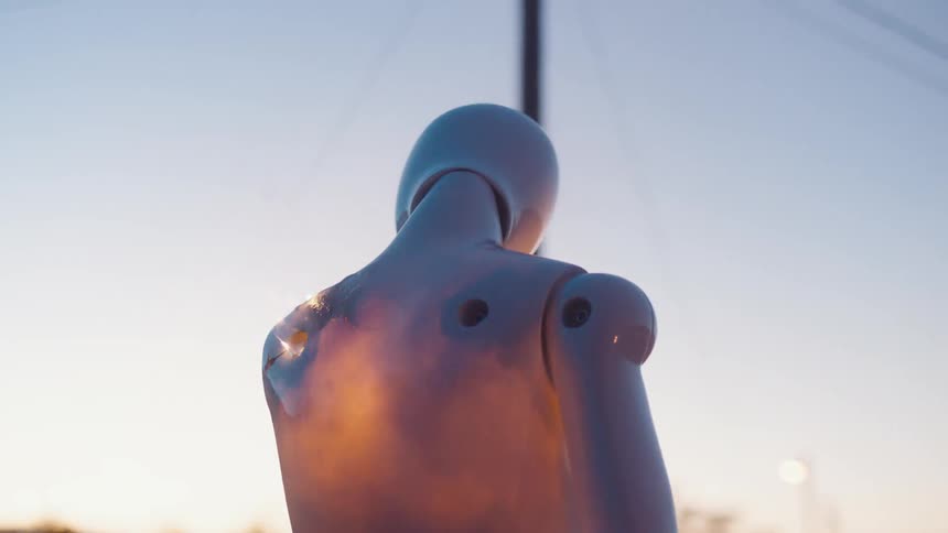 A female form mannequin with a missing arm burns on the street at dusk