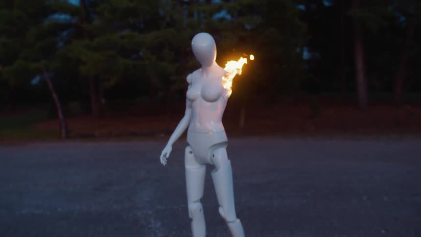 A white mannequin outdoors burns with flame