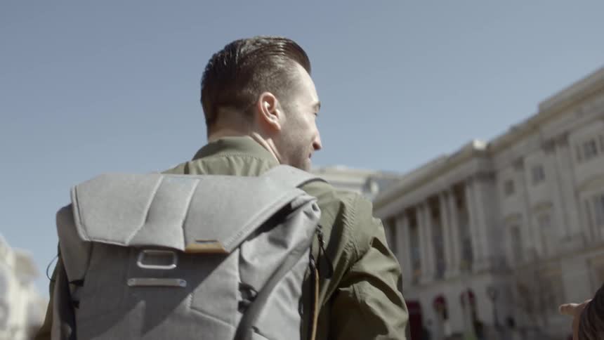 A man with a backpack walking down a street in a city