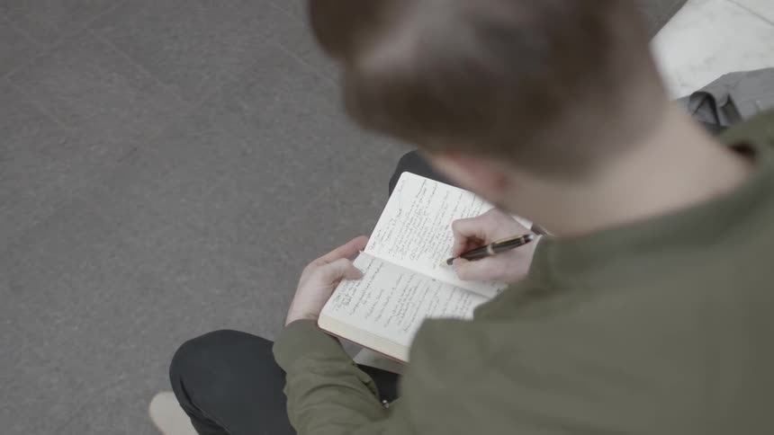A man sitting down writing in a book
