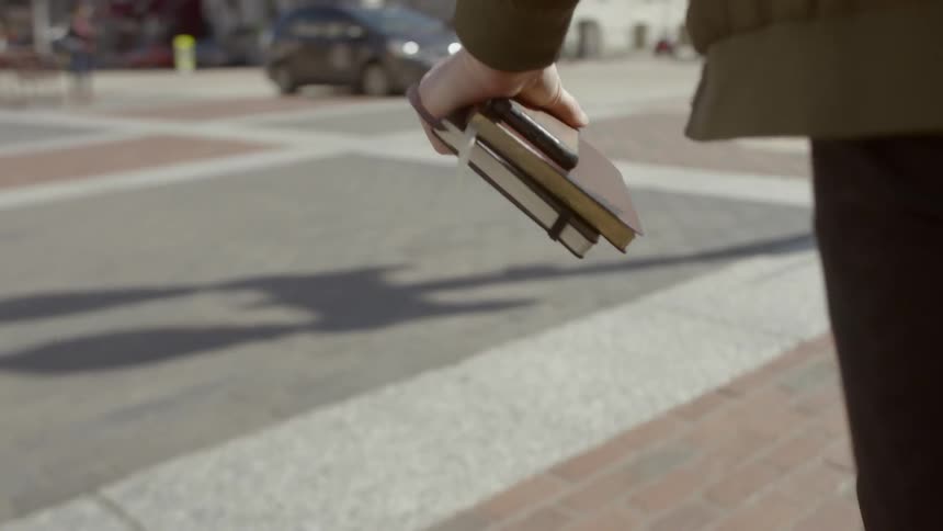 Man walking down a street holding notebook in hand