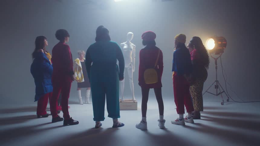 A diverse group of women stand in a circle around a female form mannequin