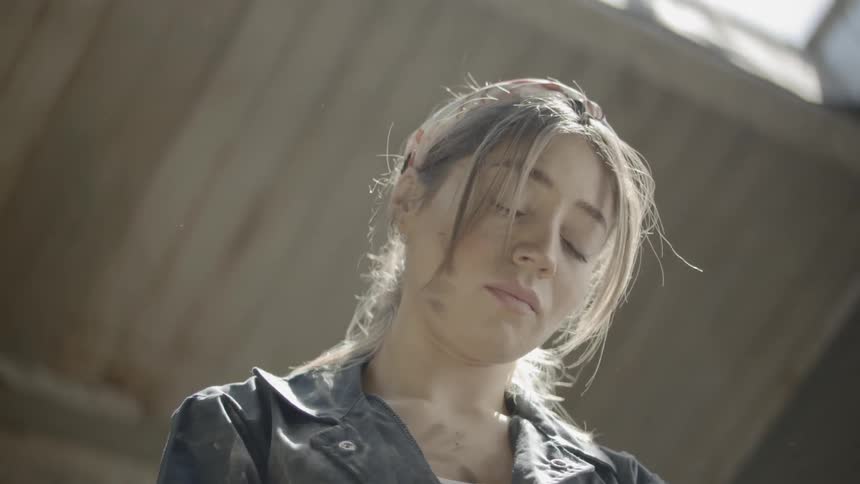A young girl looks down as she works with clay