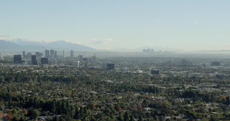 A large city is surrounded by sprawling forested suburban neighborhoods